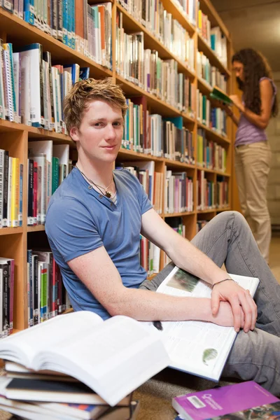 Retrato de um estudante do sexo masculino com livros, enquanto seu colega de classe é rea — Fotografia de Stock