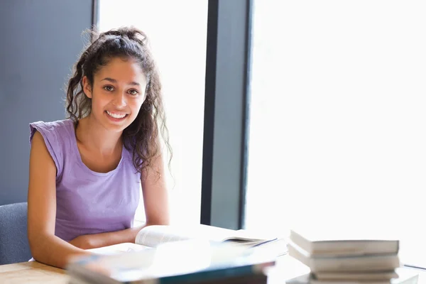 Estudante sorrindo sentado com um livro — Fotografia de Stock