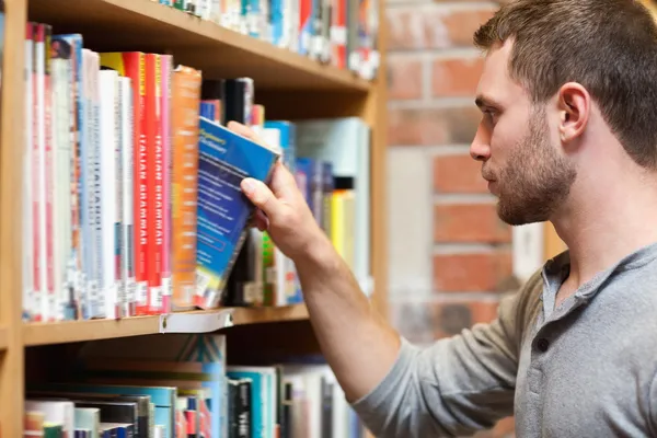Männlicher Student sucht sich ein Buch aus — Stockfoto