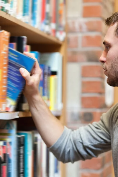 Portret van een mannelijke student plukken van een boek — Stockfoto