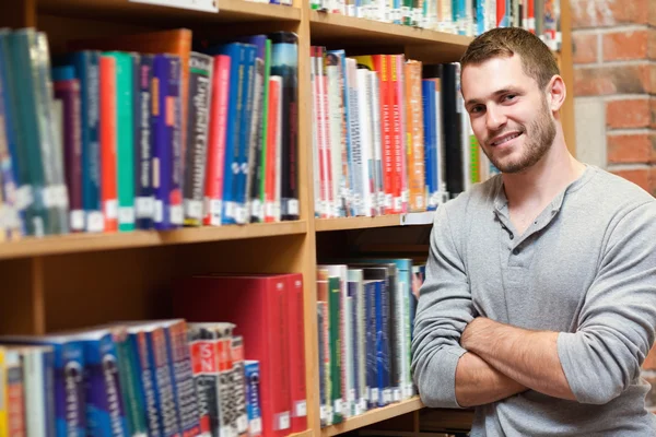 Uśmiechnięty mężczyzna studentów, opierając się na półce — Zdjęcie stockowe