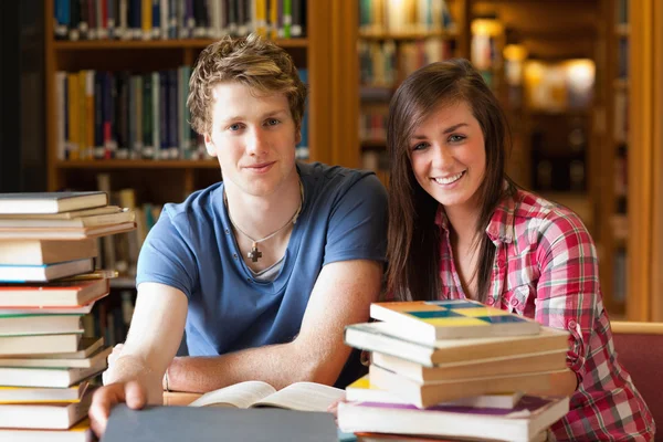 Lachende studenten omgeven door boeken — Stockfoto
