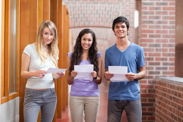 Lachende studenten houden een stuk papier — Stockfoto