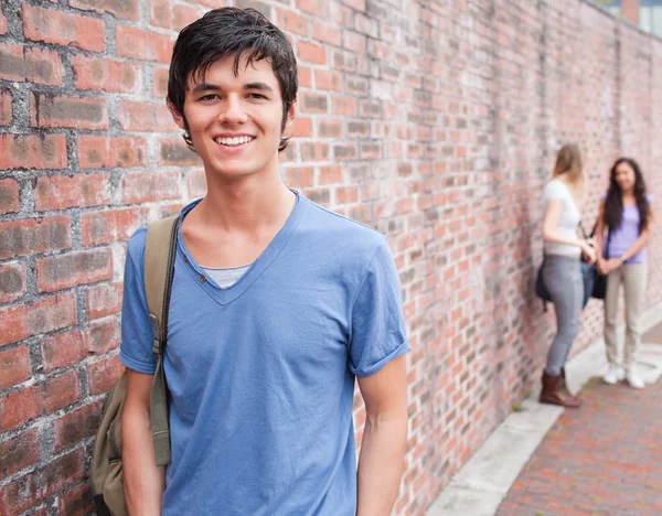 Handsome student posing while his friends are talking — Stock Photo, Image
