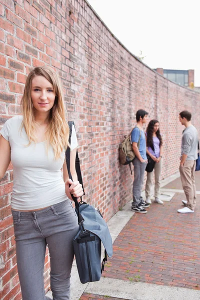 Portrait of a beautiful student posing while her friends are talking — Stock Photo, Image