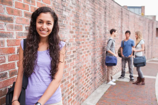 Usměvavý student pózuje, zatímco její přátelé mluví — Stock fotografie