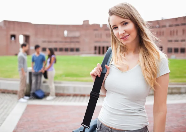Светловолосая студентка позирует, пока ее друзья разговаривают — стоковое фото