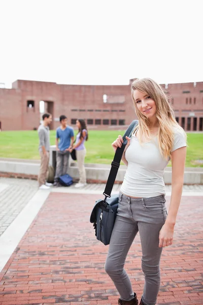 Retrato de una estudiante rubia posando mientras sus amigas hablan —  Fotos de Stock