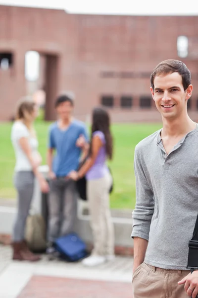 Портрет студента мужского пола, позирующего, пока его одноклассники разговаривают — стоковое фото