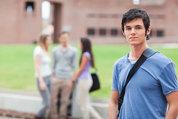 Schöner Student posiert, während seine Klassenkameraden reden — Stockfoto
