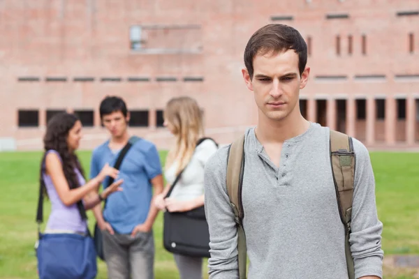 Lonely student posing while his classmates are talking — Stock Photo, Image