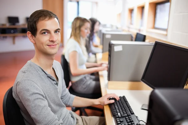 Lachende mannelijke student poseren met een computer — Stockfoto