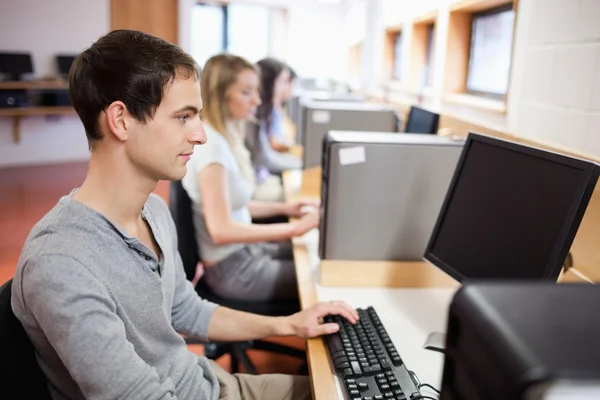 Ernstige mannelijke student werkt met een computer — Stockfoto