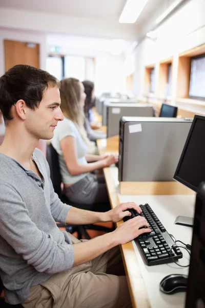 Retrato de um estudante sério do sexo masculino que trabalha com um computador — Fotografia de Stock