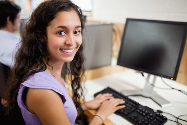 Mosolygós barna diák pózol egy számítógéppel — Stock Fotó