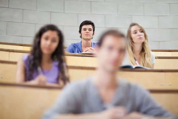 Lächelnde Studenten hören während einer Vorlesung zu — Stockfoto