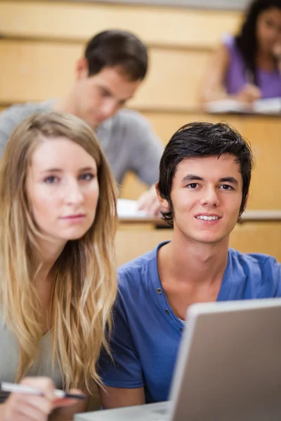Retrato de jovens estudantes posando com um laptop — Fotografia de Stock