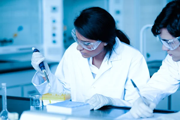 Forskare släppa vätska i provrör medan hennes partner anteckningar — Stockfoto