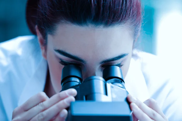 Junge Wissenschaftlerin schaut durchs Mikroskop — Stockfoto