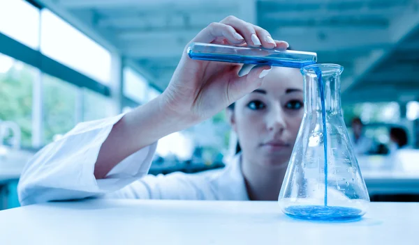 科学者が試験管でのエルレンマイヤー フラスコの液体を注ぐ — ストック写真