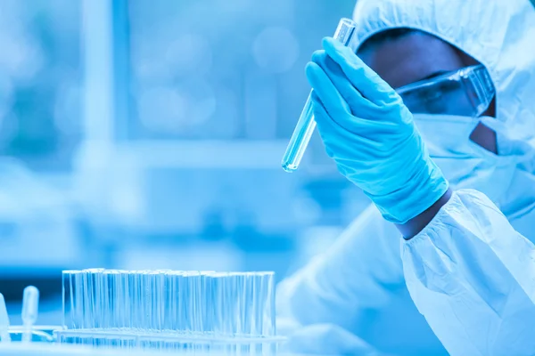 Protected scientist looking at a dangerous liquid in test tubes — Stock Photo, Image