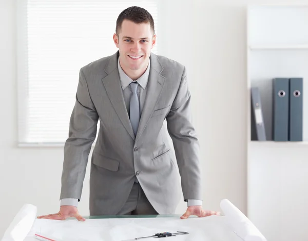 Smiling architect standing behind a table — Stock Photo, Image