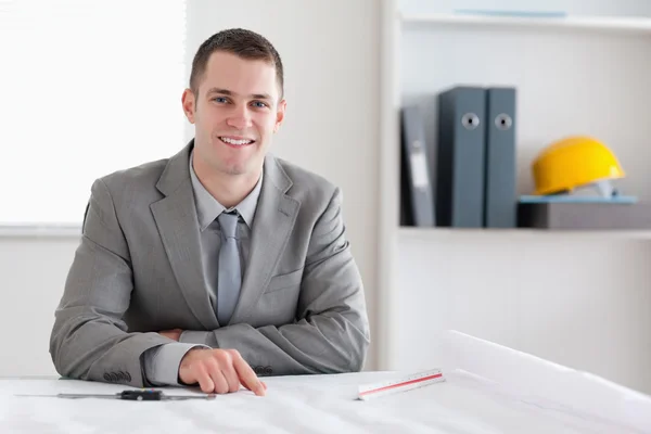 Smiling architect sitting behind a table — Stock Photo, Image