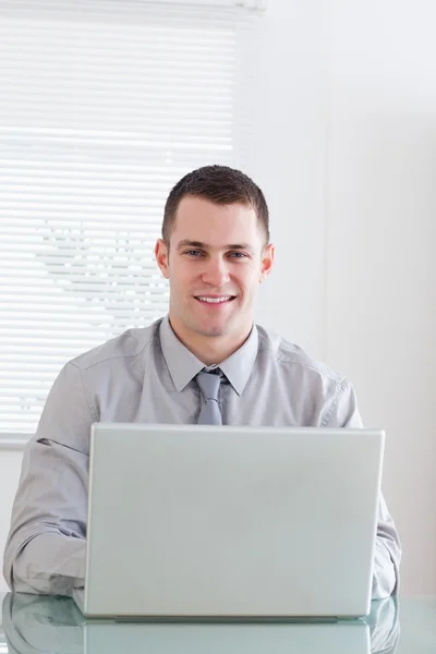 Primer plano de un hombre de negocios sonriente trabajando en su portátil — Foto de Stock