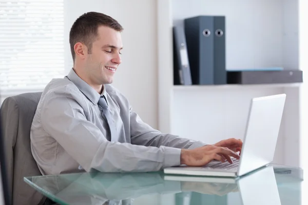 Lachende zakenman die op zijn laptop werkt — Stockfoto