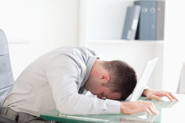 Homem de negócios sobrecarregado tirando uma soneca em seu laptop — Fotografia de Stock