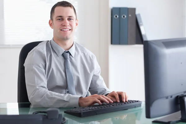 Homme d'affaires souriant tapant sur son ordinateur — Photo