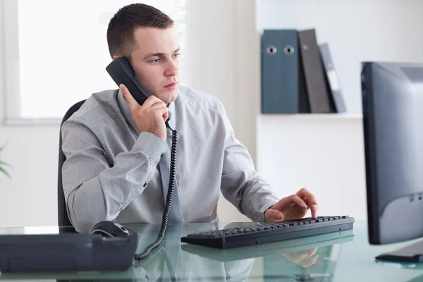 Businessman listening to caller while typing — Stock Photo, Image