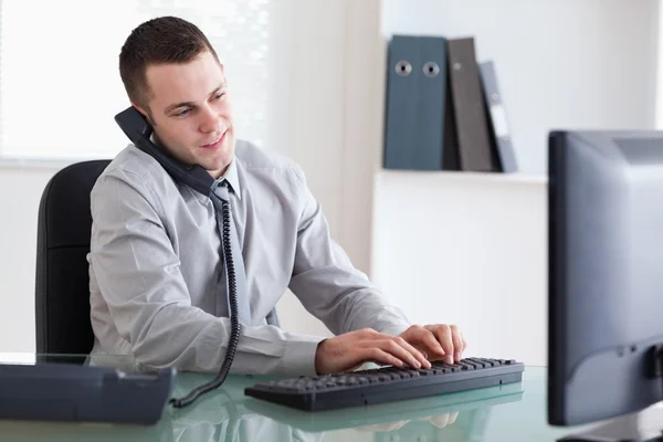 Affärsman på telefon och skriva på sin dator — Stockfoto