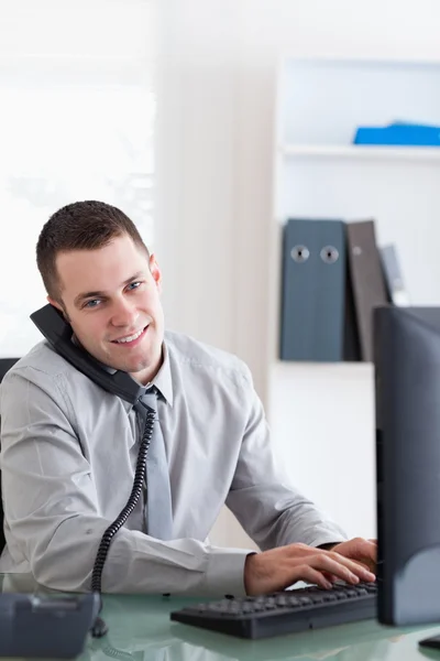 Biznesmen rozmawia przez telefon podczas korzystania z komputera — Zdjęcie stockowe