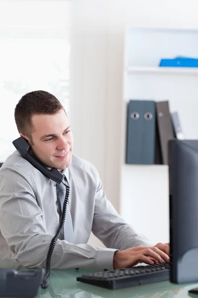 Biznesmen przy swoim komputerze podczas rozmowy przez telefon — Zdjęcie stockowe