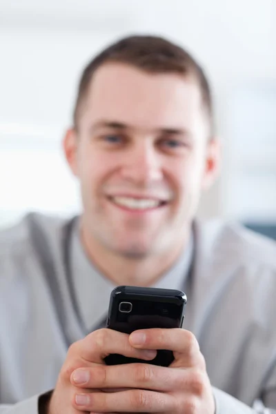 Κοντινό πλάνο κινητό τηλέφωνο που κρατούνται από τον χαμογελαστό επιχειρηματία — Φωτογραφία Αρχείου