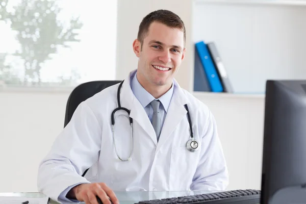 Uśmiechający się lekarza na swoim komputerze — Zdjęcie stockowe