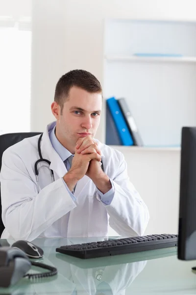 Médico pensante sentado detrás del escritorio — Foto de Stock