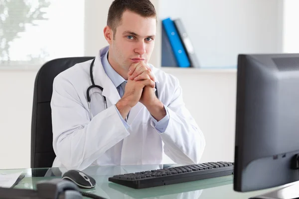 Doctor sitting behind his desk — Stock Photo, Image