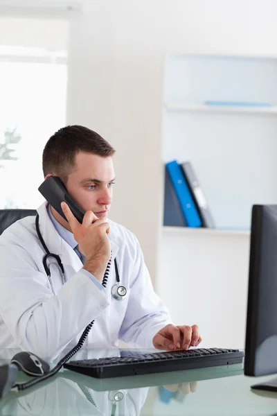 Γιατρός στο τηλέφωνο ενώ κοιτάζοντας την οθόνη — Φωτογραφία Αρχείου