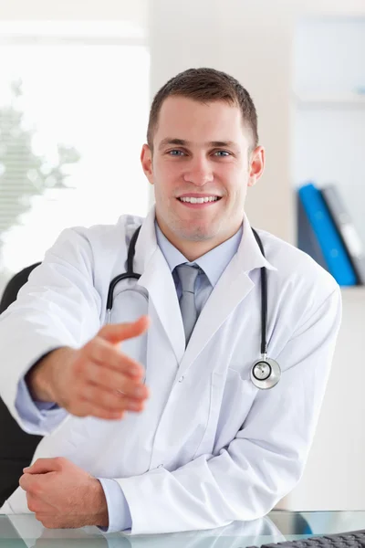 Médico sorridente estendendo a mão — Fotografia de Stock
