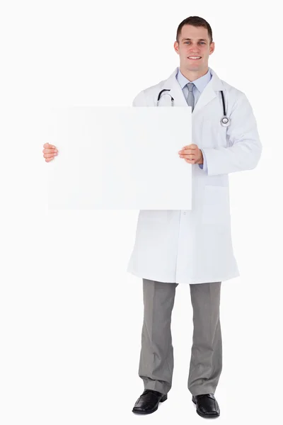 Médico de pie sosteniendo un cartel a su derecha — Foto de Stock