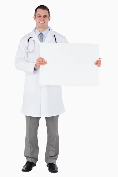 Standing doctor holding a sign to his left — Stock Photo, Image