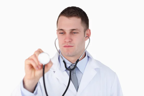 Close up of doctor looking at his stethoscope while using it — Stock Photo, Image