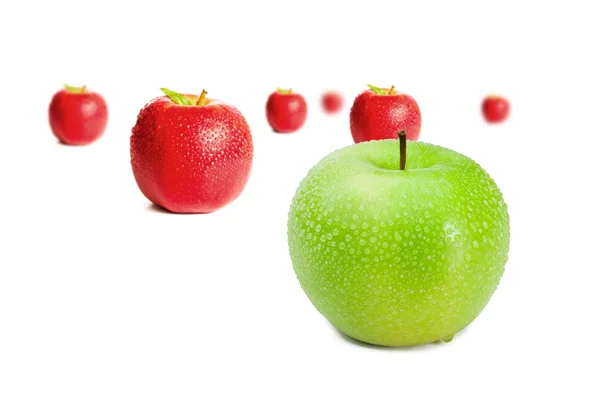 Green apple in front of red apples — Stock Photo, Image