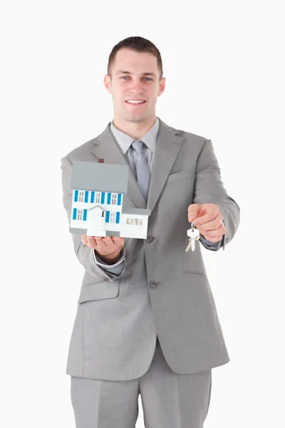 Porträtt av en affärsman som innehar en miniatyr hus och nycklar — Stockfoto