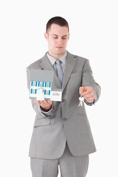 Portrait of a businessman showing a miniature house and keys — Stock Photo, Image