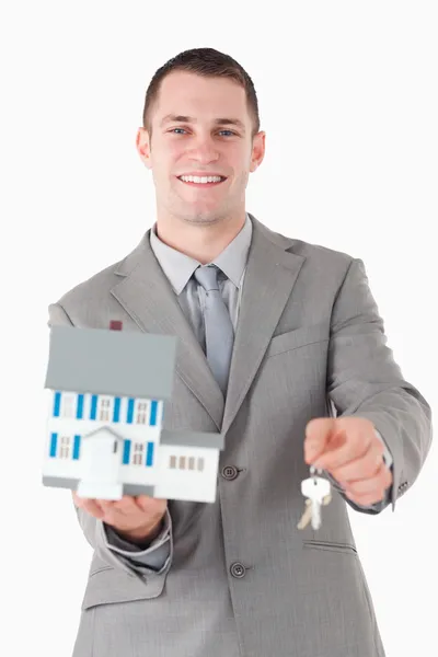Retrato de un joven empresario mostrando una casa en miniatura y ke — Foto de Stock