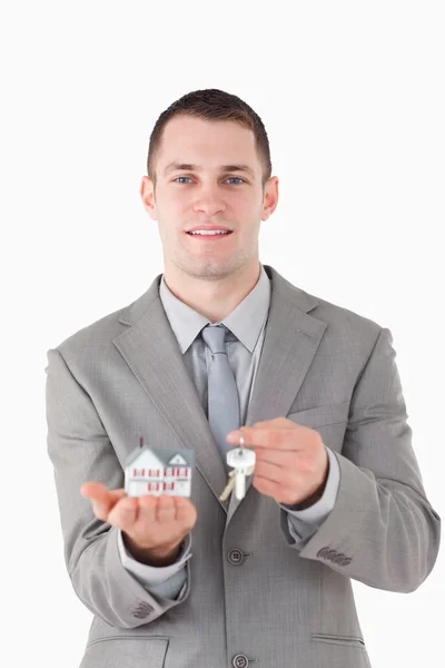 Portrait of a businessman showing a miniature house and a set of — Stock Photo, Image