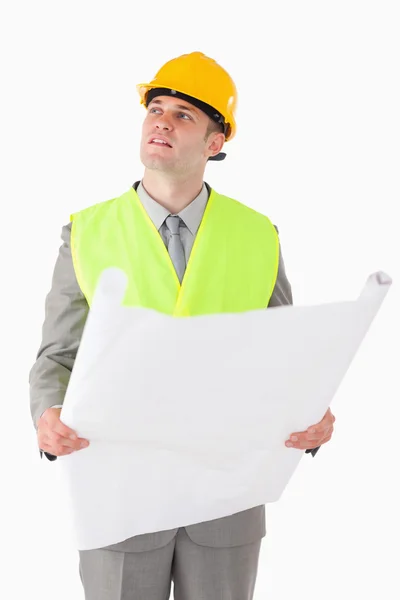 Retrato de un constructor mirando a su alrededor mientras sostiene un plan — Foto de Stock